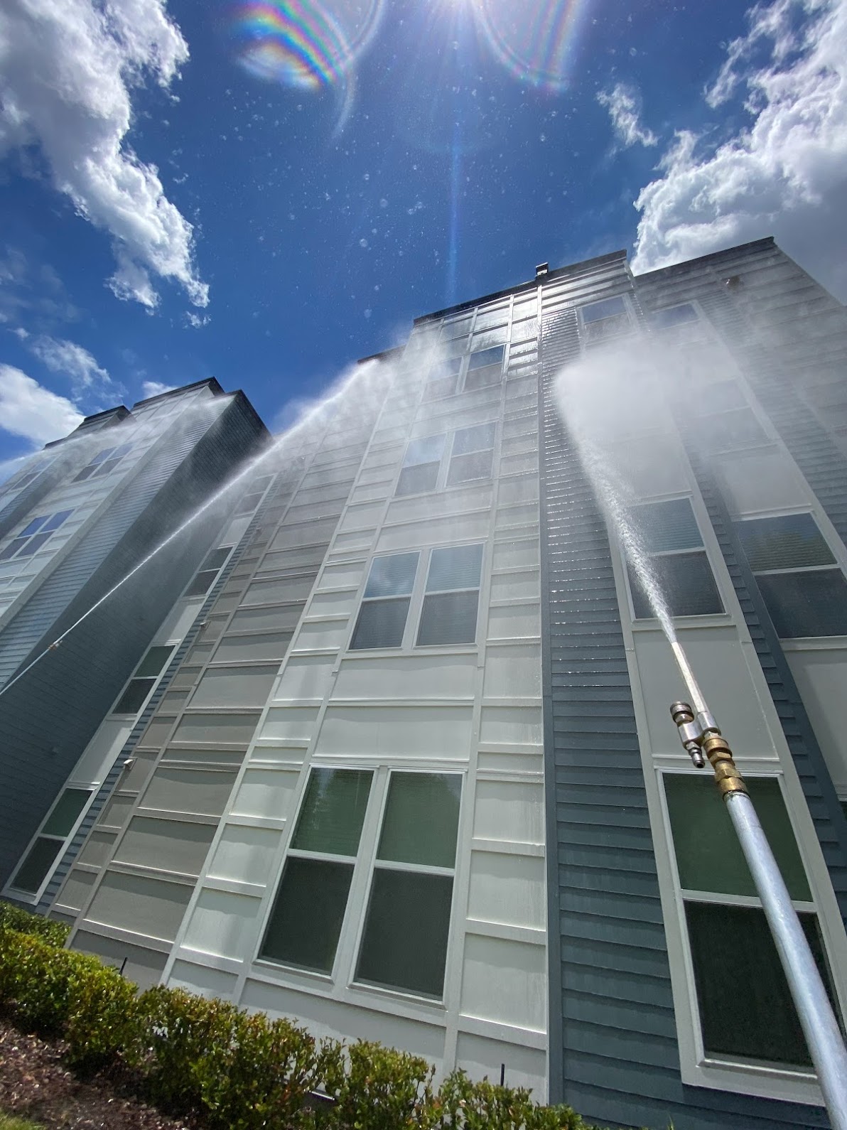 Soft wash spray reaching up several stories of a multi-story building exterior in Orlando