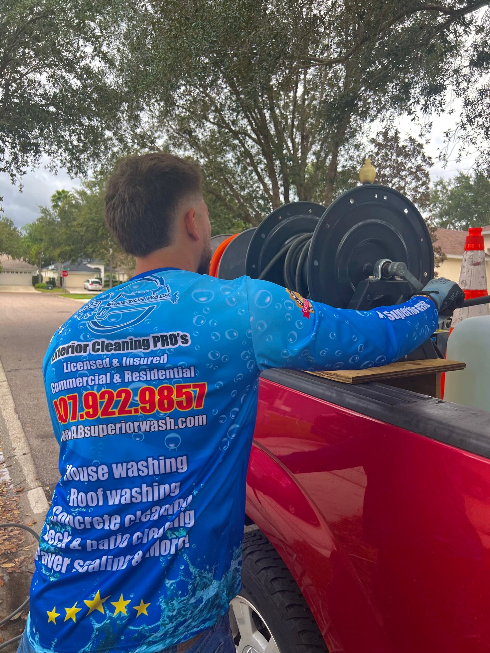 AB Superior Wash technician in branded jersey at the work truck with hose reels and tank rig in Orlando, FL